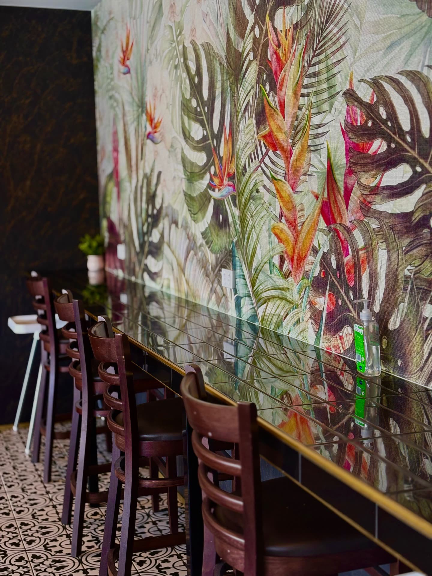 Bar seating along the mirrored ledge under the mural